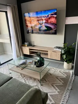 a living room with a glass coffee table and a flat screen tv at The Aura at Castle Gate in Pretoria