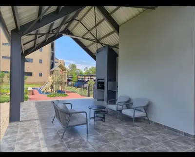 a patio with chairs and a playground in the background at The Aura at Castle Gate in Pretoria