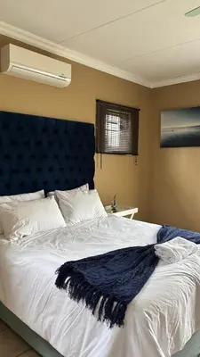a bedroom with a large bed with a blue headboard at The N1 Farm Place in Pretoria