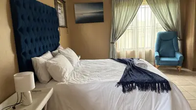 a bedroom with a large bed and a blue chair at The N1 Farm Place in Pretoria