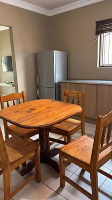 a wooden table and chairs in a kitchen with a refrigerator at The N1 Farm Place in Pretoria