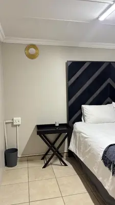 a bedroom with a bed and a side table at The N1 Farm Place in Pretoria