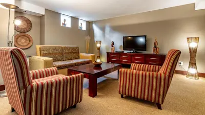 a living room with two chairs and a television at African Sky Hotels - Pine Lake Inn in White River