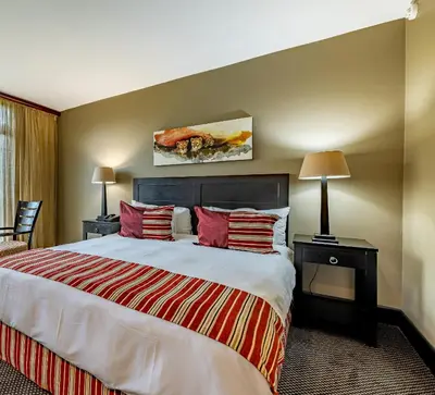 a hotel room with a large bed and two lamps at African Sky Hotels - Pine Lake Inn in White River