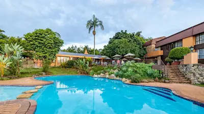 a swimming pool in front of a building at African Sky Hotels - Pine Lake Inn in White River