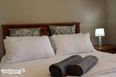 a bed with white pillows and two towels on it at Central Park in Dullstroom