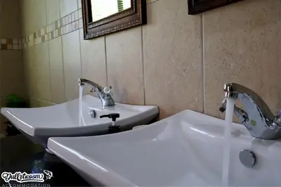 a bathroom with two white sinks and a mirror at Central Park in Dullstroom
