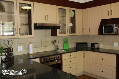 a kitchen with white cabinets and black counter tops at Central Park in Dullstroom