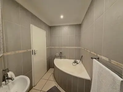 a bathroom with a bath tub and a sink at 06 Enkeldoring in Pretoria
