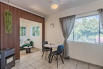 a living room with a table and chairs at Upstairs at 47 in Centurion