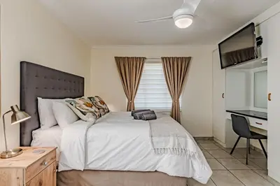 a bedroom with a large white bed with a desk at Upstairs at 47 in Centurion