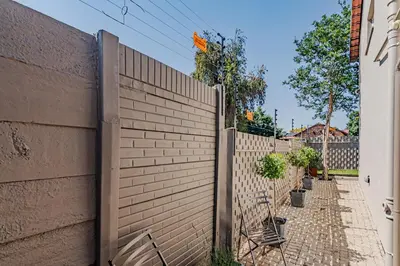 a fence next to a brick wall with potted plants at Upstairs at 47 in Centurion
