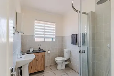 a bathroom with a toilet and a sink and a shower at Upstairs at 47 in Centurion