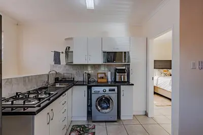 a kitchen with a stove and a washing machine at Upstairs at 47 in Centurion