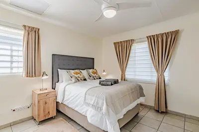 a bedroom with a large bed and windows at Upstairs at 47 in Centurion