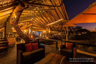 a wooden deck with two chairs and an umbrella at Ezulwini Game Lodges in Balule Game Reserve