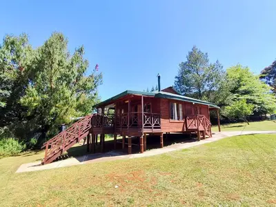 a large wooden cabin with a large deck at Fairy Cabin in Dullstroom