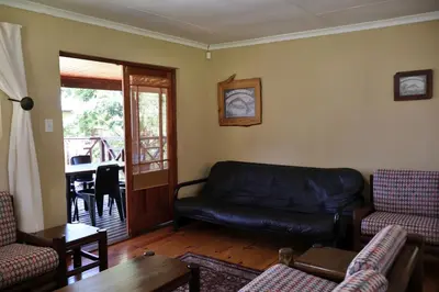 a living room with a leather couch and a table at Fairy Cabin in Dullstroom