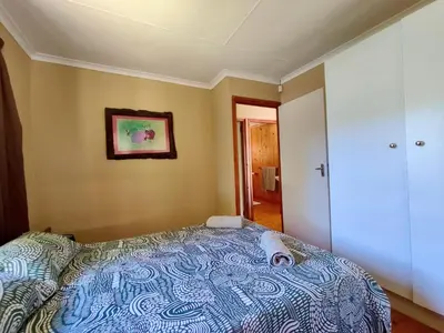 a bedroom with a bed and a painting on the wall at Fairy Cabin in Dullstroom