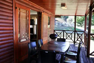 a wooden porch with a table and chairs on a balcony at Fairy Cabin in Dullstroom
