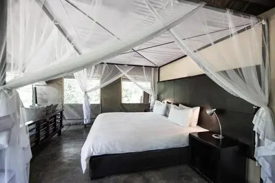 a bedroom with a canopy bed and a sink at Honeyguide Tented Safari Camp - Khoka Moya in Manyeleti Game Reserve