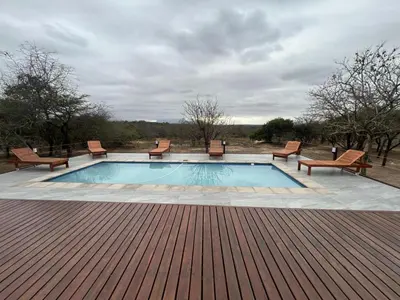 a swimming pool with chairs and a table at Cheetah Paw Safari Lodge in Guernsey Nature Reserve