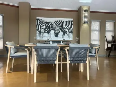 a dining room table with chairs and a painting of zebras at Cheetah Paw Safari Lodge in Guernsey Nature Reserve