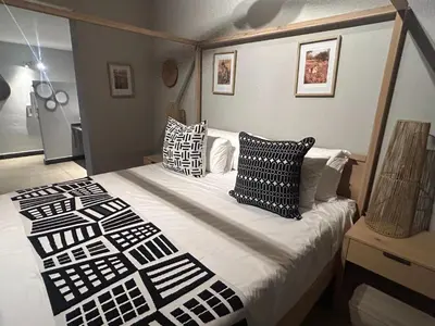 a bedroom with a bed with black and white pillows at Cheetah Paw Safari Lodge in Guernsey Nature Reserve