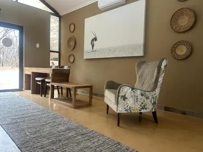 a living room with a chair and a table at Cheetah Paw Safari Lodge in Guernsey Nature Reserve