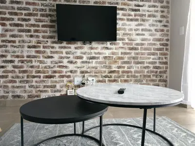 a table in a room with a tv on a brick wall at The Eyrie in Nelspruit