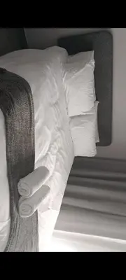 a bed with white sheets and pillows on it at The Eyrie in Nelspruit