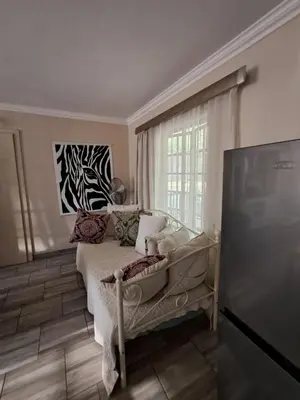 a bedroom with a bed and a large window at Sunflower Stables Cottage in the Garden in Midrand