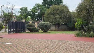 a brick driveway with a black gate in a park at Ntale Guest House in Benoni