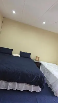 a bedroom with a large bed with blue sheets at Ntale Guest House in Benoni