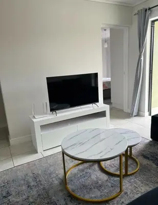 a living room with a table and a tv at East Luxe BNB 2bed 2bath in Pretoria