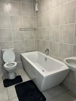 a bathroom with a tub and a toilet and a sink at East Luxe BNB 2bed 2bath in Pretoria
