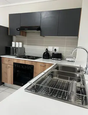 a kitchen with a sink and a dish rack at East Luxe BNB 2bed 2bath in Pretoria