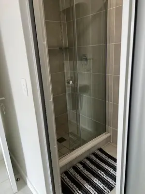 a shower with a glass door with a rug at East Luxe BNB 2bed 2bath in Pretoria