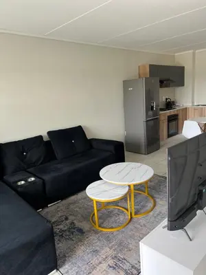 a living room with a black couch and a table at East Luxe BNB 2bed 2bath in Pretoria
