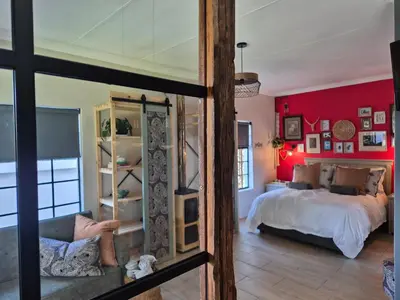 a bedroom with a bed and a red wall at Hibiscus at Bougainvillea House in Pretoria