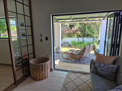 a living room with a door open to a patio at Hibiscus at Bougainvillea House in Pretoria
