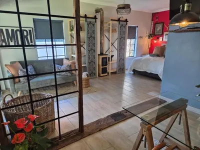 a living room with a bed and a glass table at Hibiscus at Bougainvillea House in Pretoria