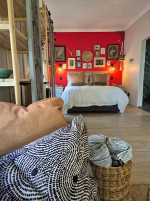 a bedroom with a bed with a red wall at Hibiscus at Bougainvillea House in Pretoria