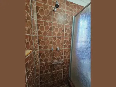 a bathroom with a shower with a stone wall at Kruger Boutique Backpackers in Marloth Park