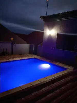 a blue swimming pool at night with a house at Madiva Nelspruit Guest House in Nelspruit