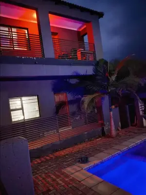 a house with a palm tree next to a swimming pool at Madiva Nelspruit Guest House in Nelspruit