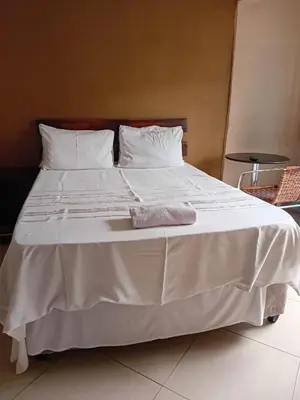 a large white bed with a towel on it at Madiva Nelspruit Guest House in Nelspruit