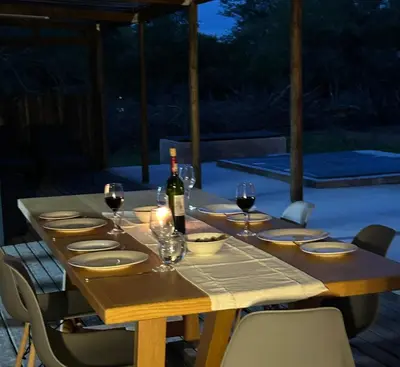 a wooden table with a bottle of wine and glasses at One Eight Seven on Moepel in Malelane