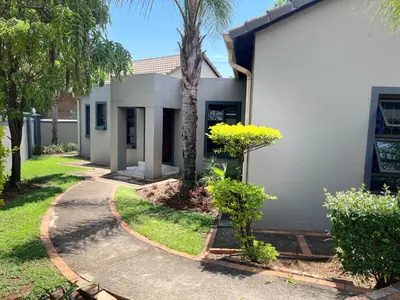 a house with a palm tree next to a driveway at Crown Guesthouse Meyerspark in Pretoria