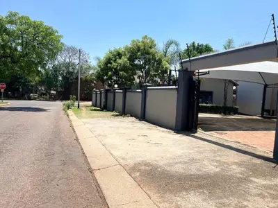 an empty street with a fence next to a building at Crown Guesthouse Meyerspark in Pretoria